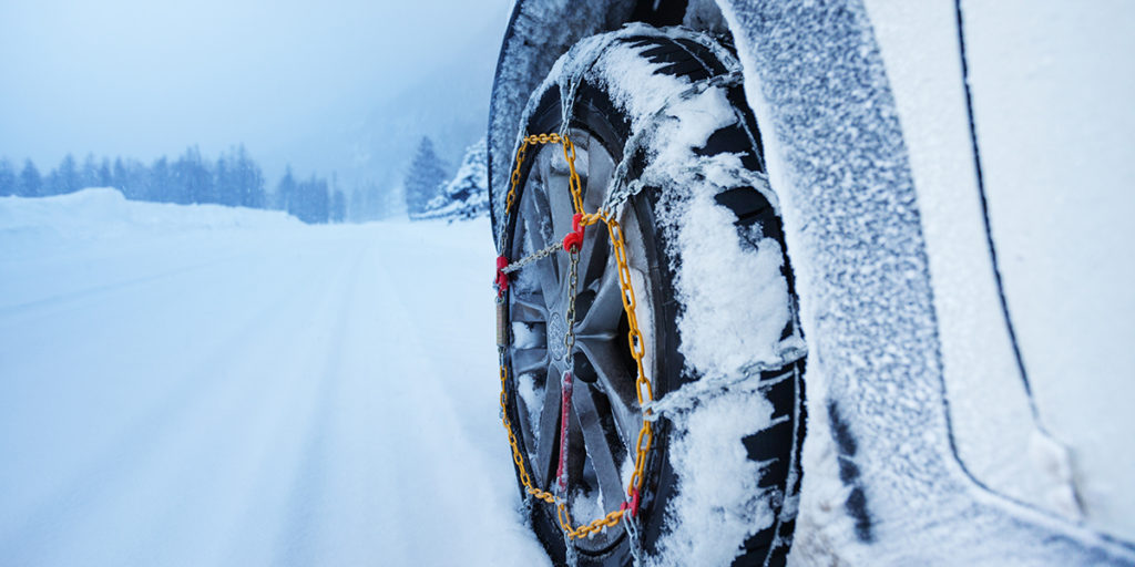 car with tire chains driving through deep snow
