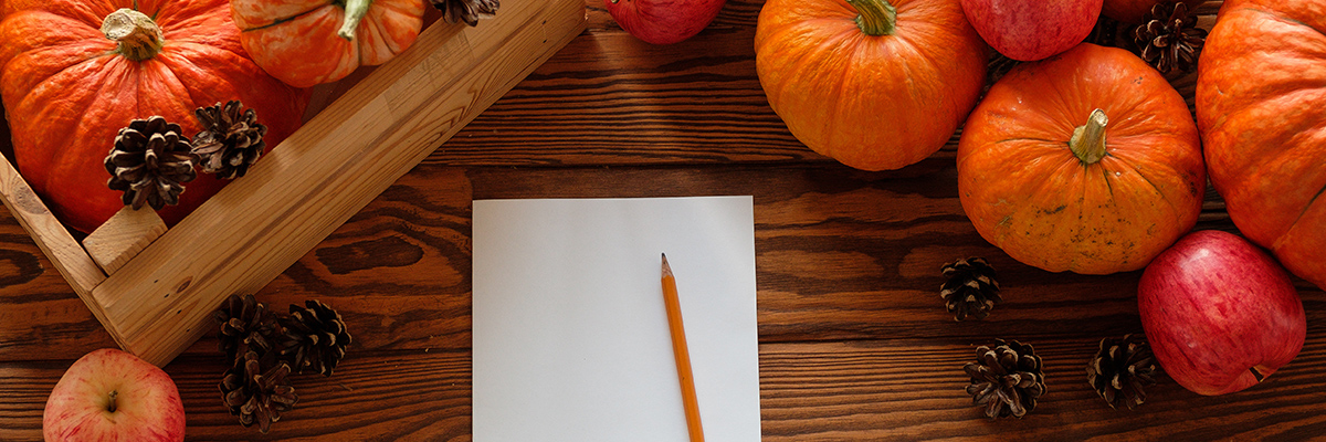 Pencil on blank paper next to fall pumpkins