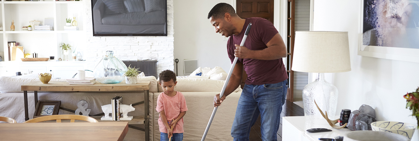 Father and son sweeping up inside home