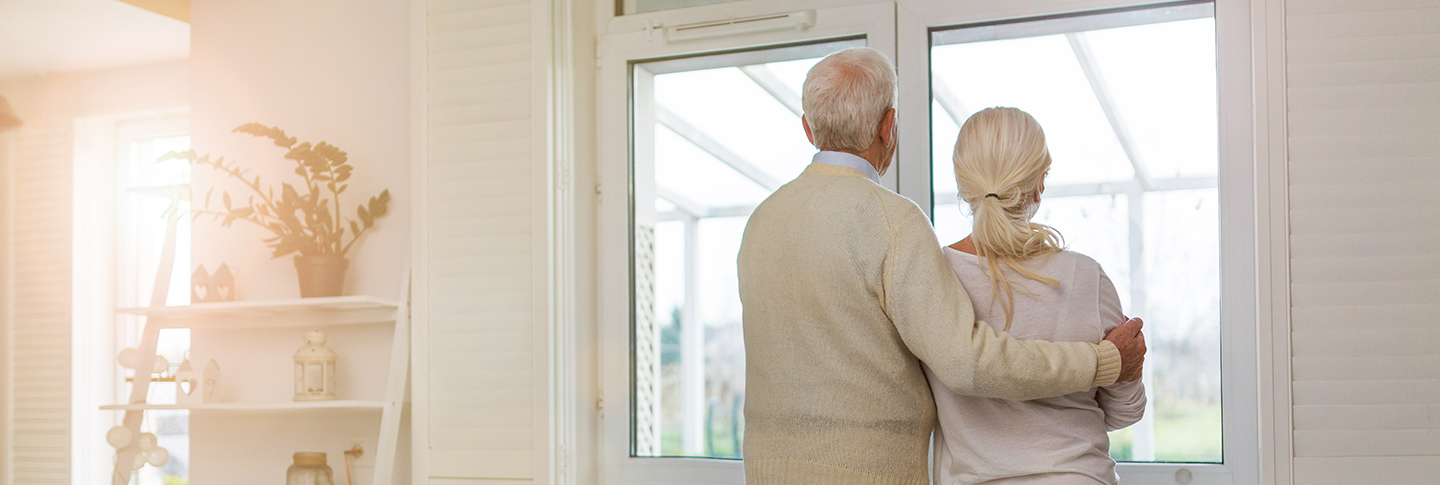 Senior couple looking out window of home