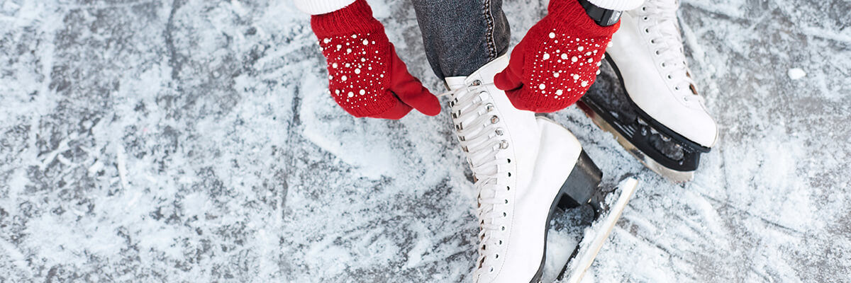 Gloved hands lacing up ice skates